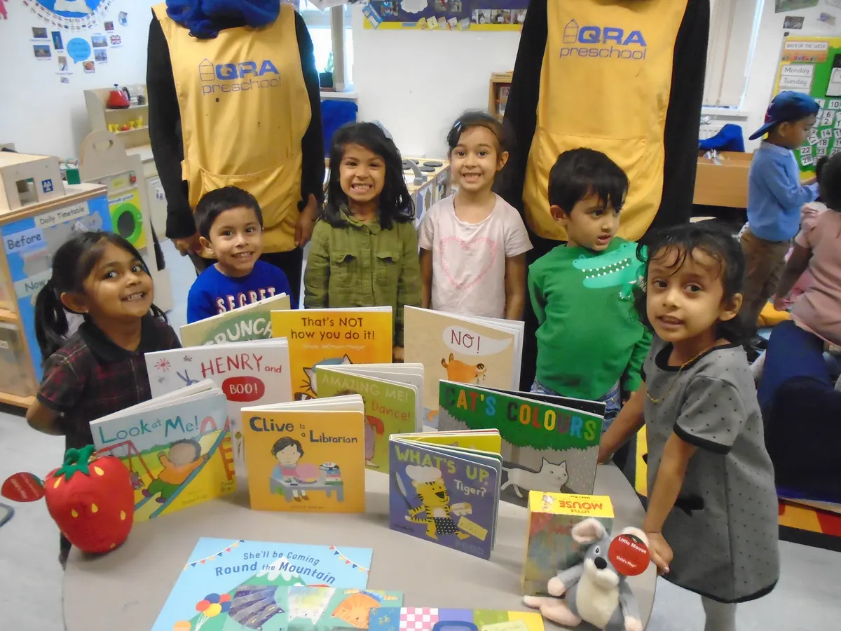 Children proudly showing their favourite picture books alongside Iqra Preschool staff