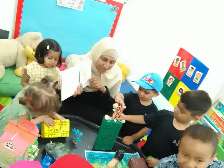 A staff member reading and doing craft activities with a group of children at Iqra Preschool Poplar