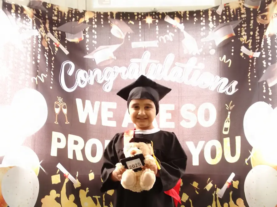 A proud child in a graduation cap and gown at their Iqra Preschool graduation celebration